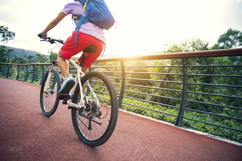 Woman cyclist riding Mountain Bike on forest trail
